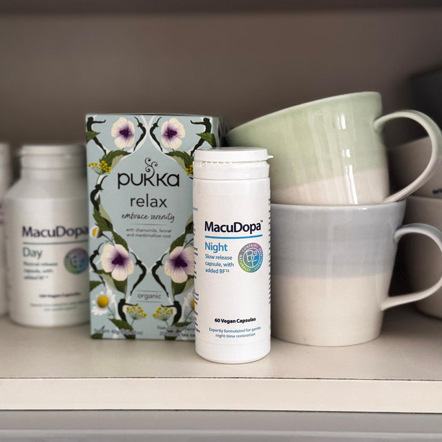 A shelf displaying a bottle of MacuDopa Night slow-release capsules alongside a box of Pukka Relax herbal tea and two ceramic mugs stacked inside each other.